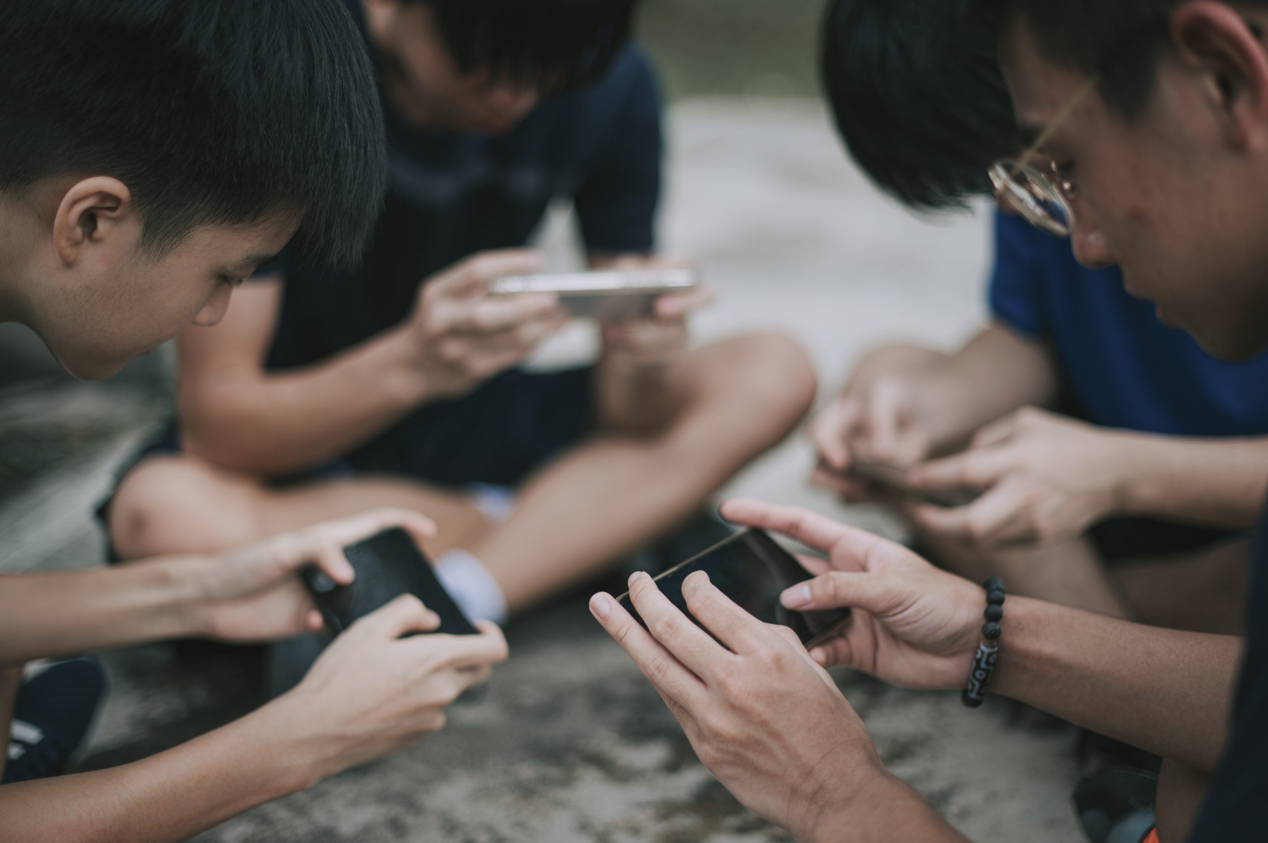 An Asian Chinese Group Of Teenage Boys Playing Mobile Game In The Basketball Court After School Using Phone Generation Z