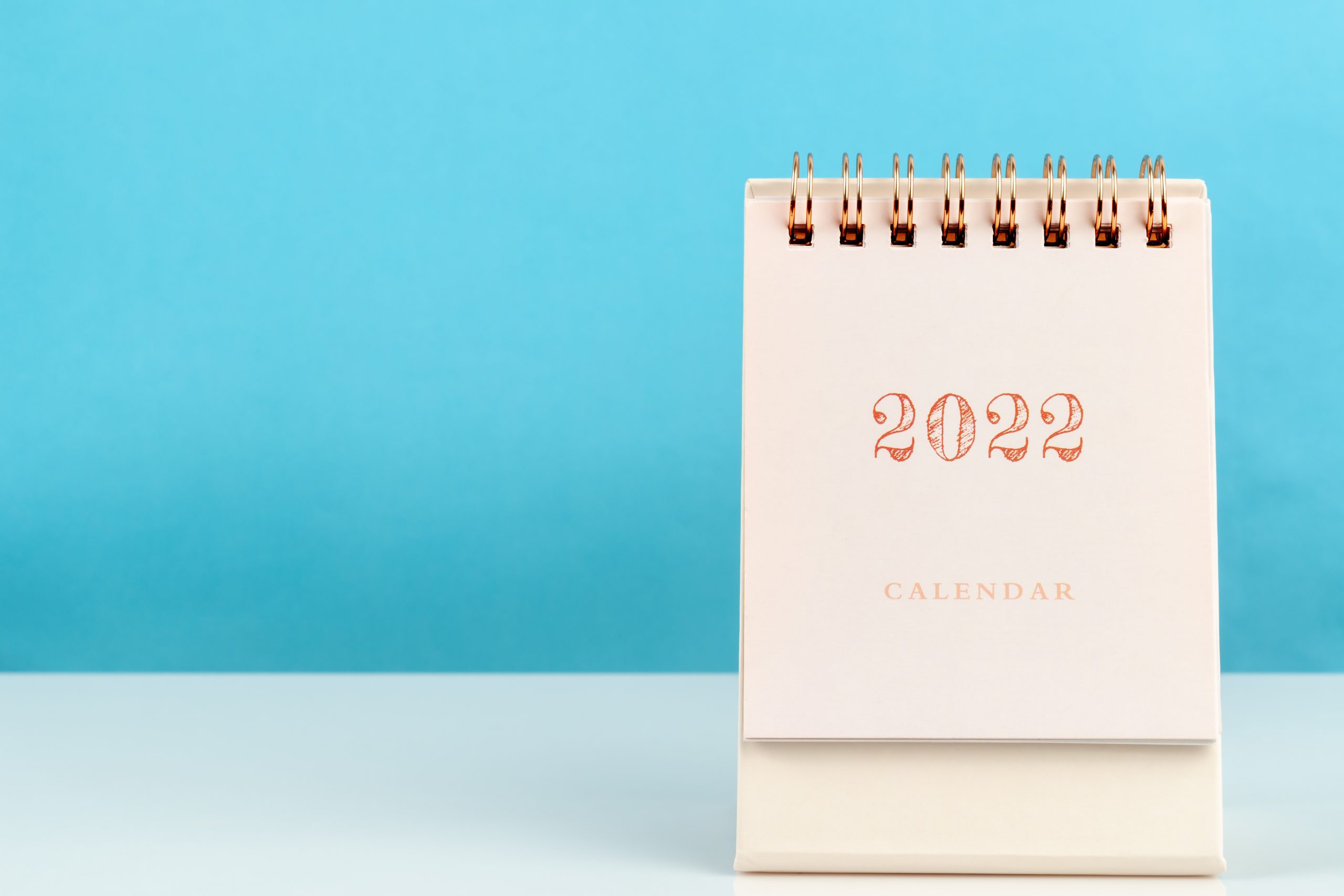 Calendar Desk 2022 For Organizer To Plan And Reminder On Wooden Table With Blue Color Background.